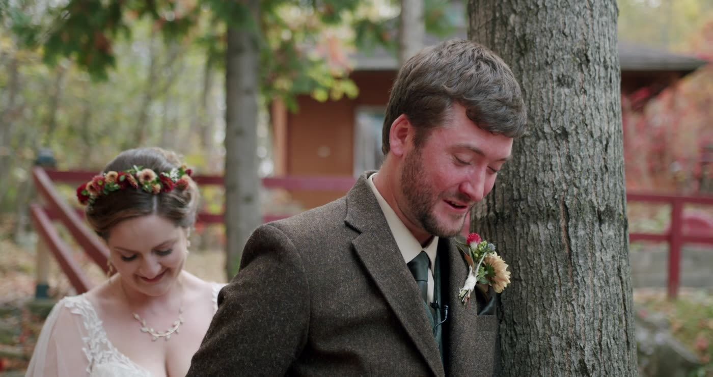 A groom laughing as he sees his bride
