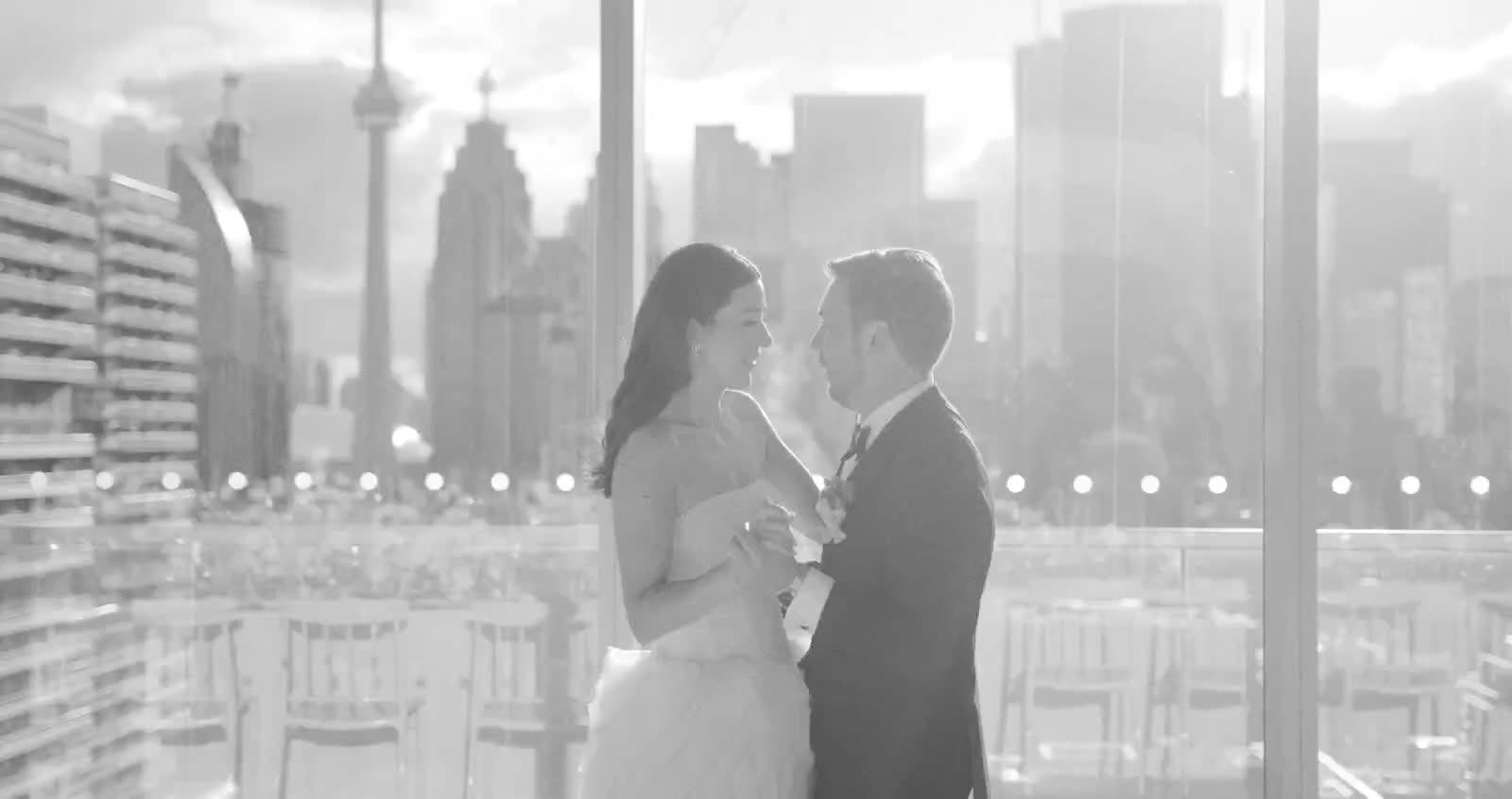 A couple dancing in black and white in front of tall windows